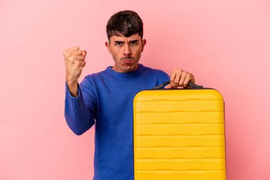 Genç melez adam pembe arka planda tek başına seyahat edecek yumruğunu kameraya gösterecek, agresif yüz ifadesi..