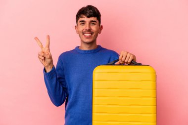 Genç melez adam pembe arka planda tek başına seyahat edecek. İki numarayı parmaklarıyla gösteriyor..
