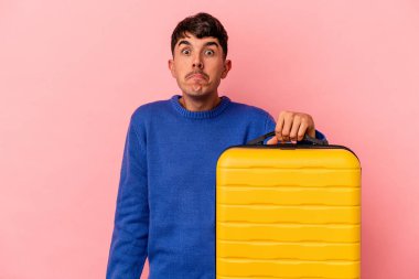 Genç melez adam pembe arka planda tek başına seyahat edecek omuzlarını silkeleyecek ve gözleri açık kalacak..