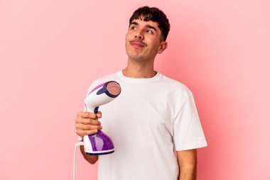 Pembe arka planda demir tutan genç melez adam hedeflerine ve amaçlarına ulaşma hayali kuruyor.