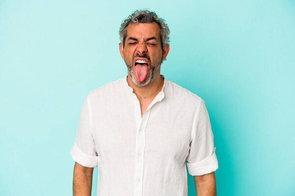 Middle age caucasian man isolated on blue background  funny and friendly sticking out tongue.