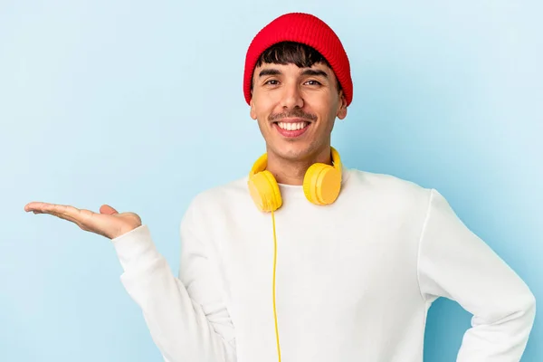 Mladý Smíšený Závod Muž Poslouchá Hudbu Izolované Modrém Pozadí Ukazující — Stock fotografie