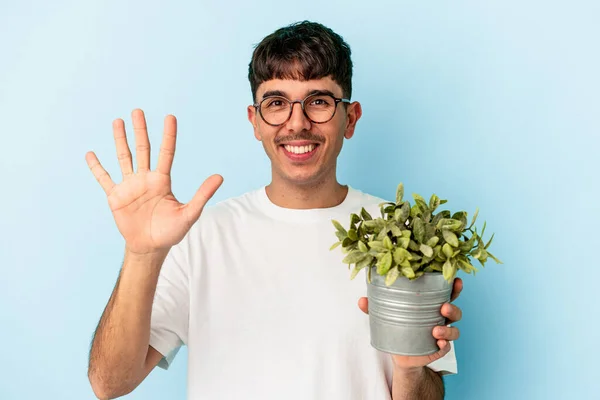Joven Hombre Raza Mixta Sosteniendo Una Planta Aislada Sobre Fondo — Foto de Stock