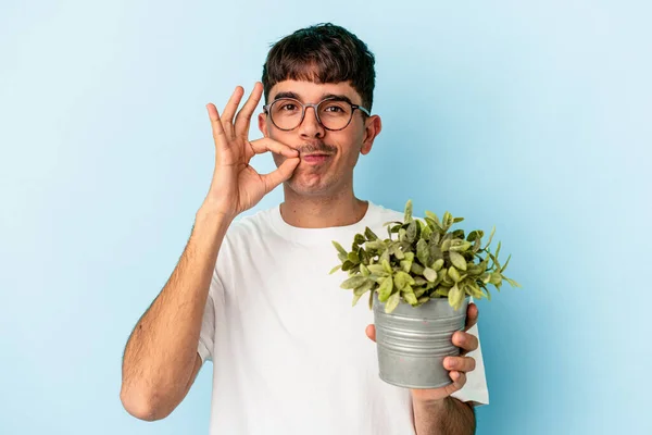 Jonge Gemengde Ras Man Met Een Plant Geïsoleerd Blauwe Achtergrond — Stockfoto