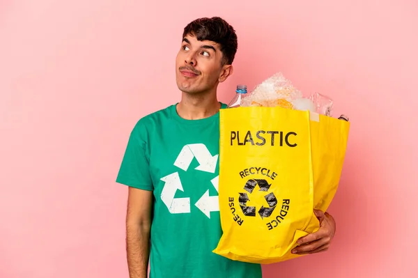 Jonge Gemengde Ras Man Gerecycleerd Plastic Geïsoleerd Roze Achtergrond Dromen — Stockfoto