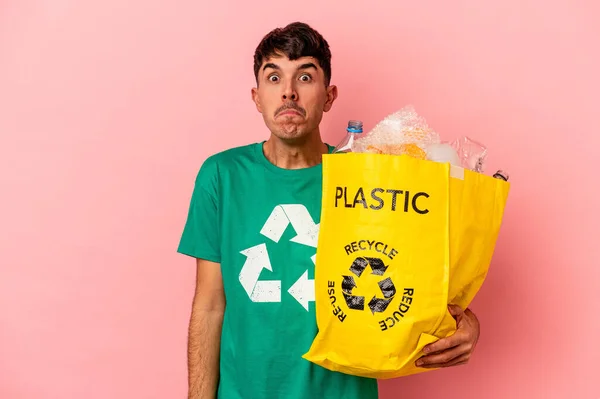Jonge Gemengde Ras Man Gerecycled Plastic Geïsoleerd Roze Achtergrond Haalt — Stockfoto