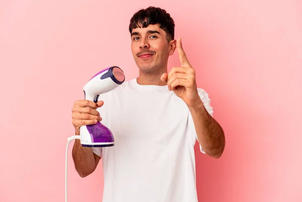 Young Mixed Race Man Holding Iron Isolated Pink Background Showing — Stock Photo, Image