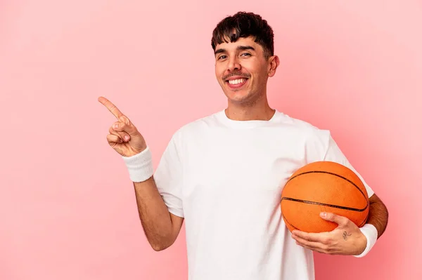 Mladý Míšenec Hraje Basketbal Izolovaný Růžovém Pozadí Usmívá Ukazuje Něco — Stock fotografie