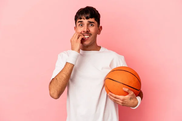 Mladý Smíšený Závod Muž Hraje Basketbal Izolované Růžovém Pozadí Kousání — Stock fotografie