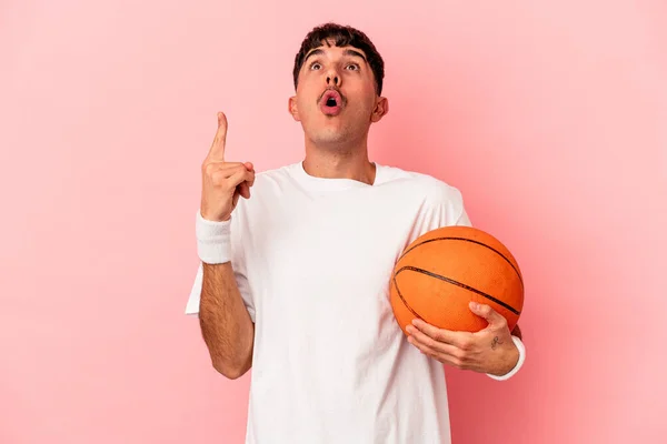 Młody Mieszany Wyścig Człowiek Gra Koszykówkę Odizolowany Różowym Tle Wskazując — Zdjęcie stockowe