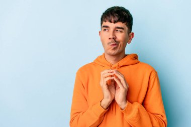 Genç melez adam mavi arka planda izole edildi. Aklında bir fikir oluşturdu..