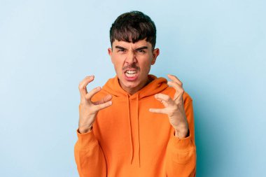 Genç melez adam mavi arka planda izole edilmiş gergin ellerle çığlık atıyor..