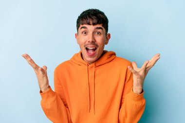 Genç melez adam mavi arka planda izole edilmiş gökyüzüne haykırıyor, yukarı bakıyor, hayal kırıklığına uğramış..