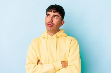 Genç melez adam mavi arka planda izole edildi. Tekrarlanan bir görevden yoruldu..