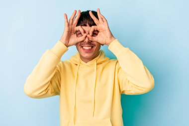 Genç melez adam mavi arka planda izole edildi.