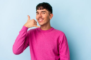 Genç melez adam mavi arka planda izole edildi. Parmakları olan bir cep telefonu hareketi gösteriyor..