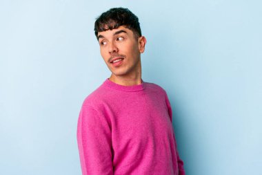 Mavi arka planda soyutlanmış genç bir ırk. Gülümsüyor, neşeli ve keyifli görünüyor..