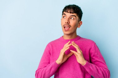 Genç melez adam mavi arka planda izole edildi. Aklında bir fikir oluşturdu..