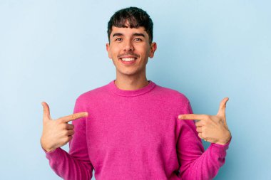 Genç melez adam mavi arka planda izole edilmiş parmakları aşağıda, olumlu hisler içinde..