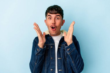 Genç melez adam mavi arka planda izole edildi. Şaşırdı ve şok oldu..