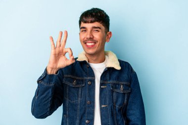 Genç melez adam mavi arka planda izole edildi. Neşeli ve kendinden emin..