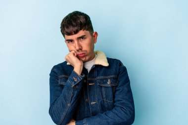 Genç melez adam mavi arka planda izole edildi. Tekrarlanan bir görevden yoruldu..