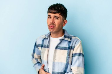 Genç melez adam mavi arka planda izole edilmiş karaciğer ağrısı, mide ağrısı var..