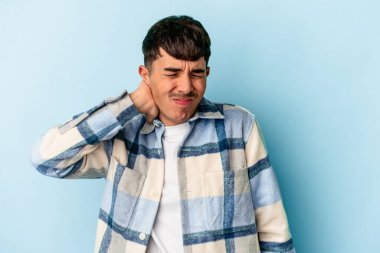 Genç melez adam mavi arka planda izole edildi. Stres yüzünden boynu ağrıyor, masaj yapıyor ve elle dokunuyor..