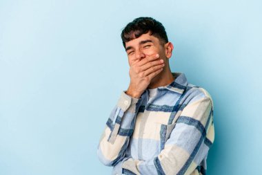 Genç melez adam mavi arka planda izole edilmiş gülen, kaygısız, doğal duygulara sahip..