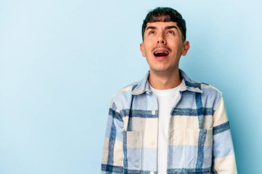 Genç melez adam mavi arka planda izole edilmiş çok kızgın, öfkeli, hayal kırıklığına uğramış.