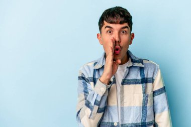 Genç melez adam mavi arka planda izole edilmiş gizli bir sıcak fren haberinin olduğunu ve kenara baktığını söylüyor.