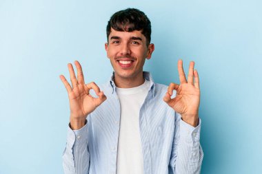 Genç melez adam mavi arka planda izole edildi. Neşeli ve kendinden emin..