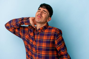 Genç melez adam mavi arka planda izole edilmiş dirsek masajı yapıyor, kötü bir hareketin ardından acı çekiyor..