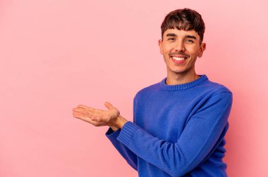 Pembe arka planda izole edilmiş genç bir ırk. Elinde palmiyesinde bir kopyası var..