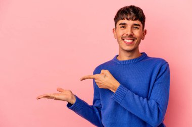 Genç melez adam, pembe arka planda izole edilmiş. Heyecanlı, elinde bir kopyası var..