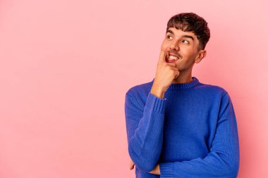 Genç melez adam pembe arka planda izole edilmiş rahat bir şekilde fotokopi odasına bakan bir şey düşünüyor..