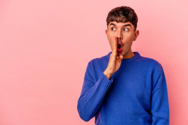 Genç melez adam pembe arka planda izole edilmiş gizli bir fren haberinin olduğunu söylüyor.