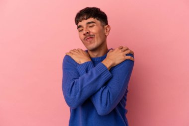 Genç melez adam pembe arka planda izole edilmiş. Kucaklaşma, kaygısız gülümseme ve mutluluk..