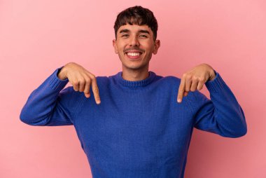 Genç melez adam pembe arka planda izole edilmiş parmakları aşağıda, olumlu hisler içinde..