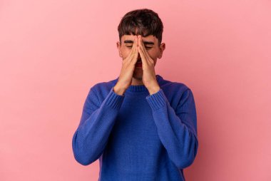 Genç melez bir adam pembe arka planda izole edilmiş, el ele tutuşmuş, ağzının kenarında dua ediyor, kendinden emin..