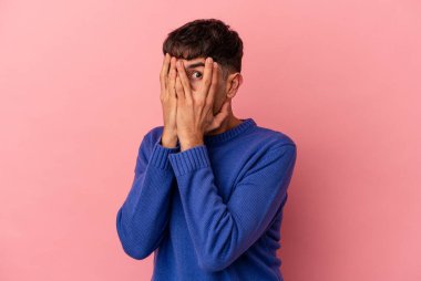 Genç melez adam pembe arka planda izole edilmiş parmaklarıyla gözünü kırp korkmuş ve gergin..