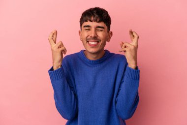 Genç melez adam pembe arka planda izole edilmiş şans dilemek için şans diliyor.