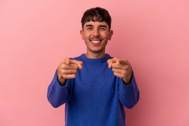 Genç melez adam pembe arka planda soyutlanmış neşeli gülümsemeler öne bakıyor..