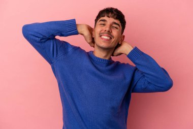 Genç melez adam pembe arka planda izole edilmiş, kollarını uzatmış, rahat bir konumda..