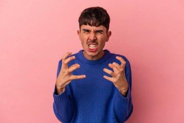 Genç melez adam pembe arka planda izole edilmiş gergin ellerle çığlık atıyor..