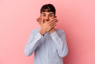 Pembe arka planda izole edilmiş genç melez adam elleriyle ağzını kapatırken şok oldu..