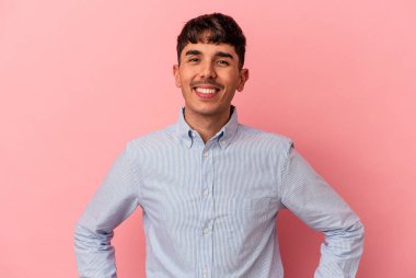 Genç melez adam pembe arka planda izole edilmiş. Kendine güvenen, ellerini kalçasında tutan..