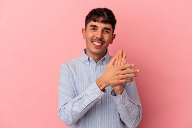 Genç melez adam pembe arka planda izole edilmiş enerjik ve rahat hissediyor, ellerini ovuşturuyor kendinden emin..