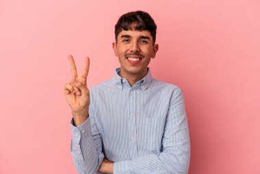 Genç melez adam pembe arka planda izole edilmiş iki numarayı parmaklarıyla gösteriyor..