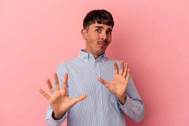 Genç melez adam, pembe arka planda izole edilmiş, tiksinti gösteren birini reddediyor..